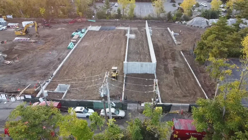 Drone photo of Avalon Quincy project with foundation footprint, utility piping, and excavators on graded site
